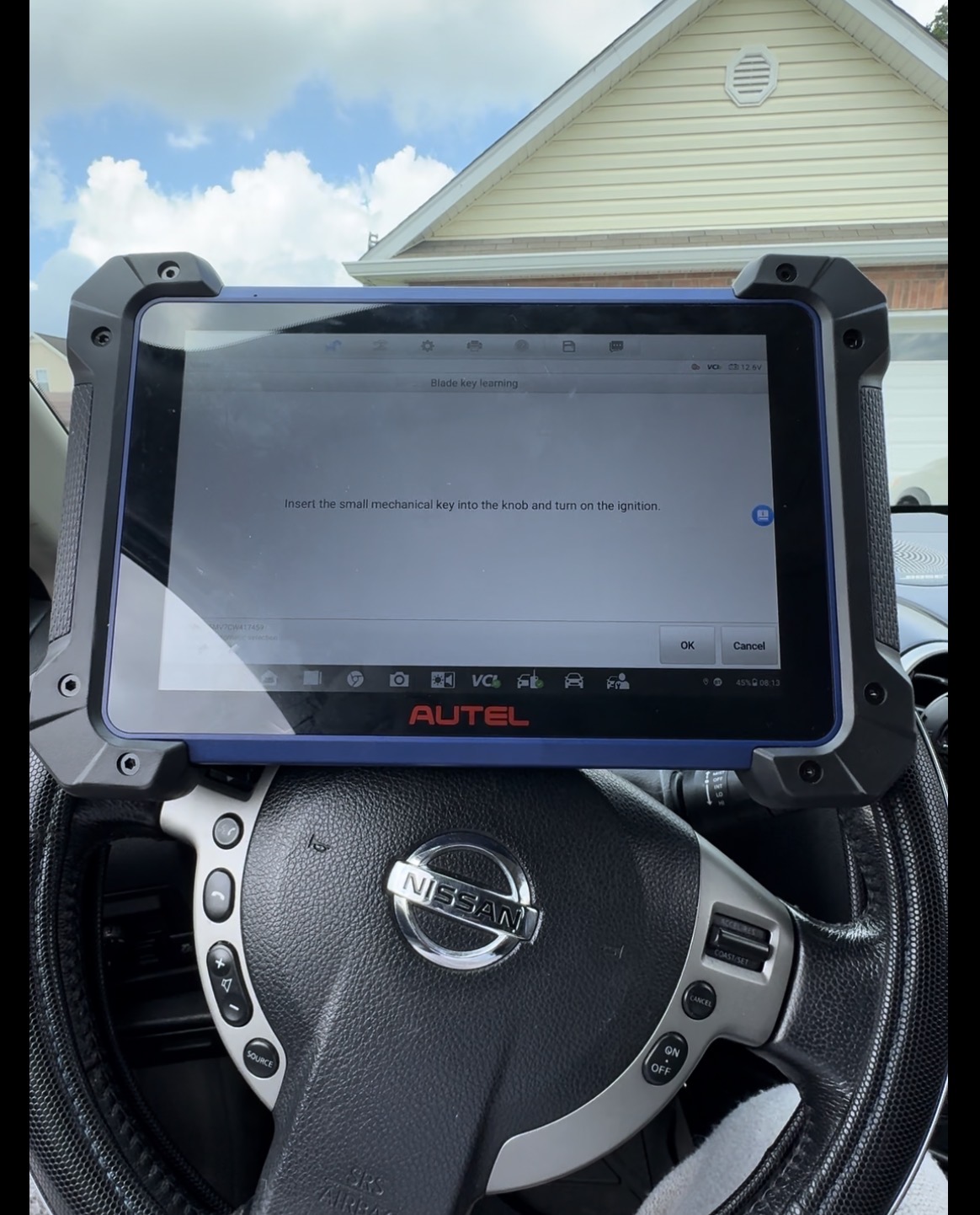 Automotive locksmith programming a key with a diagnostic tablet mounted on a steering wheel